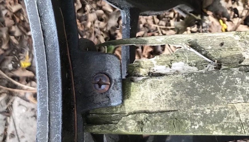 Detail der verwitterten Gartenbank: rostige Schraube in morschem Holz