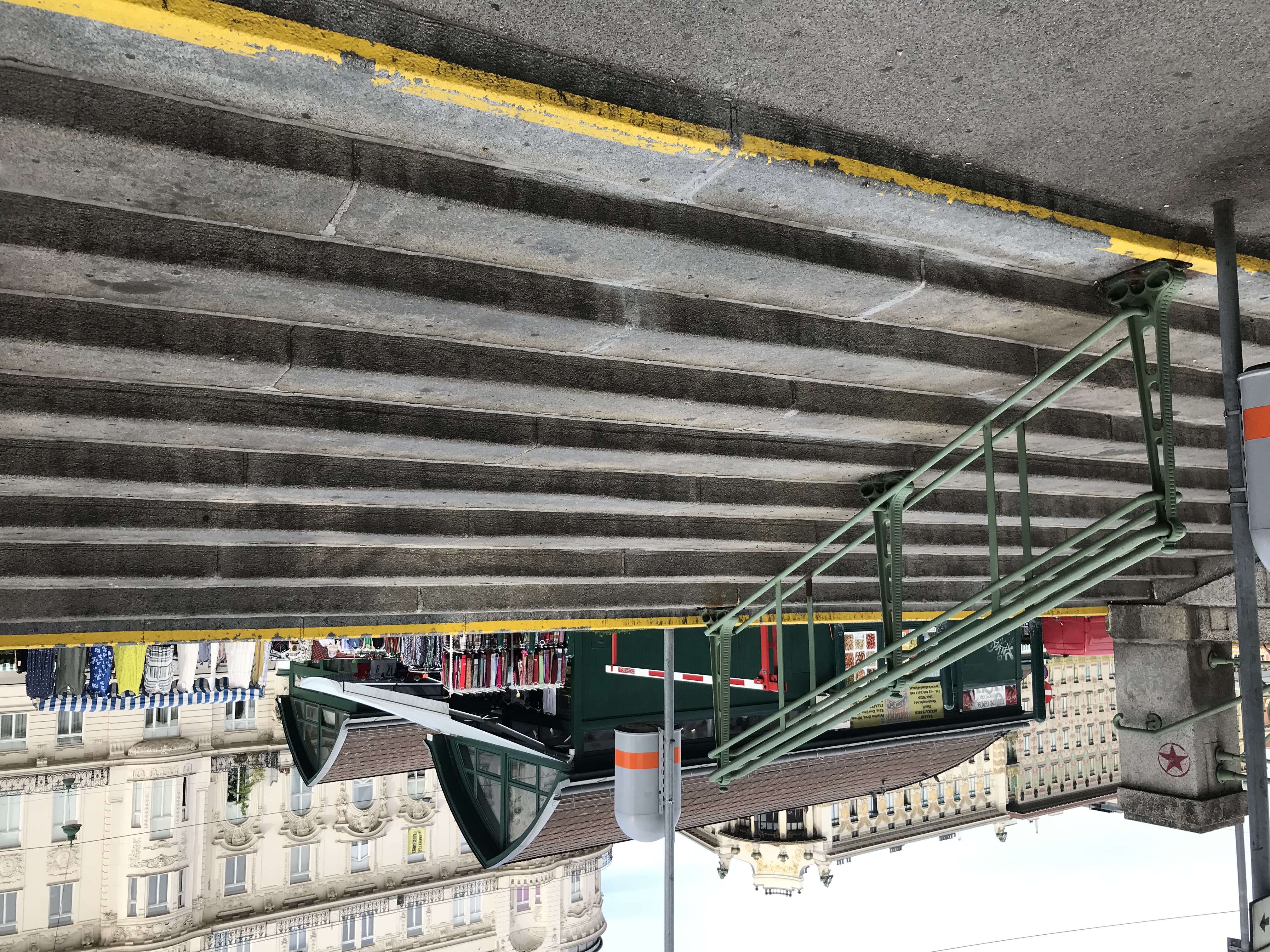 Farbfoto: Stiegenanlage von einem Gehweg weg, oben sind Marktstände zu sehen.
